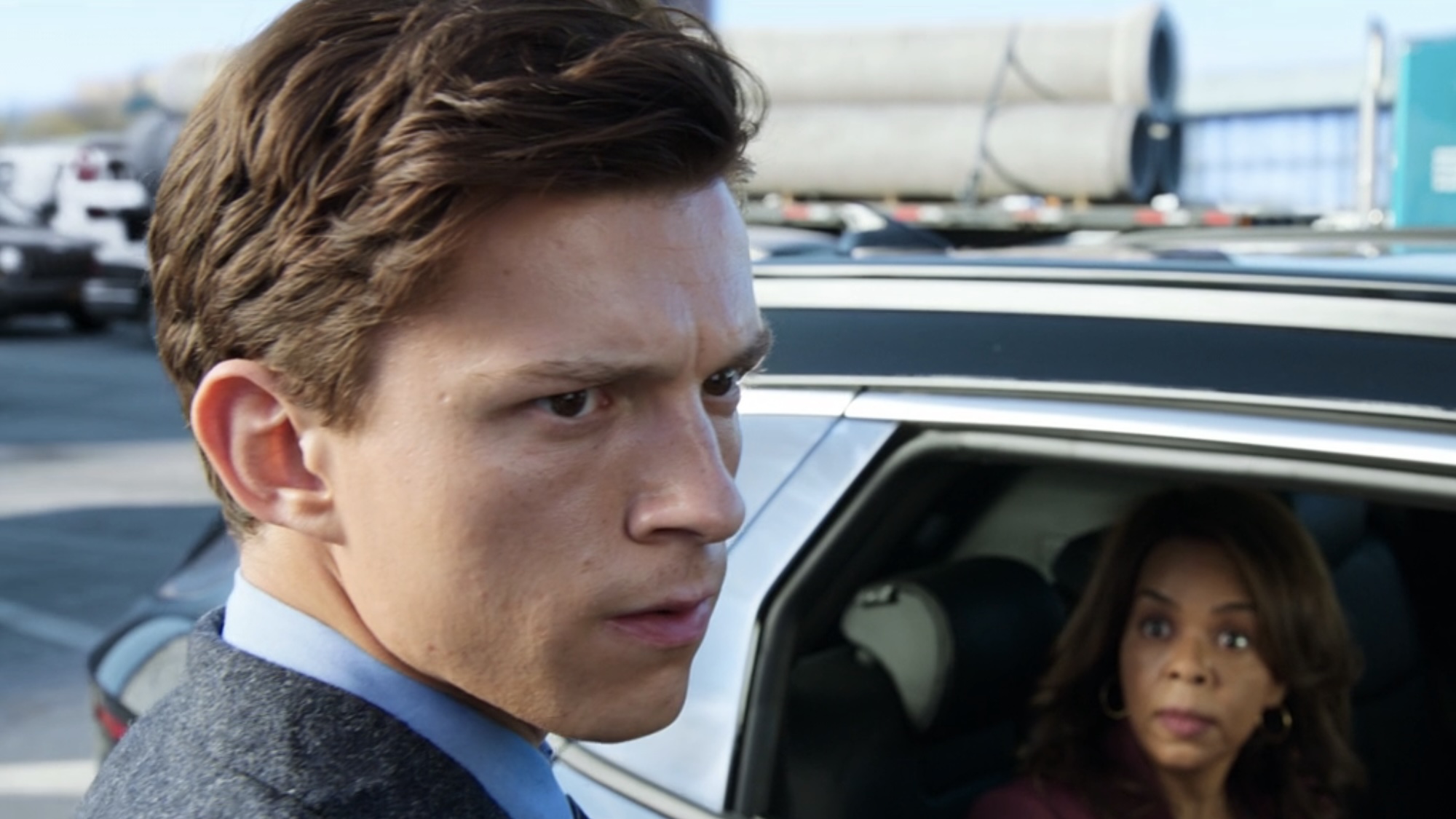 Peter wearing his wrinkled blazer and looking concerned over his spider-sense, while the MIT woman watches from her car.