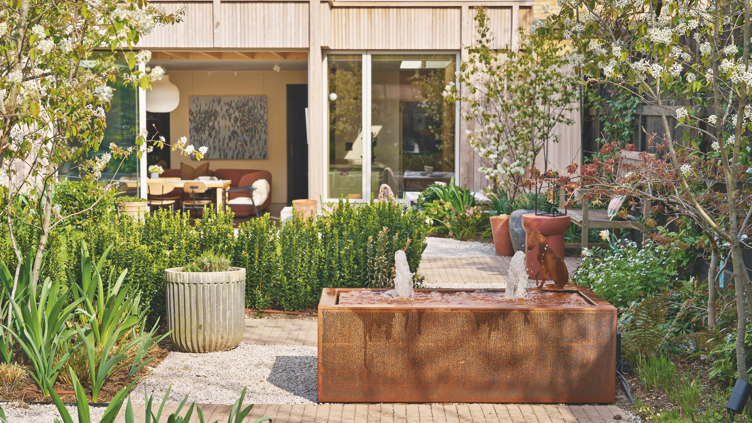 Exterior view of the house and garden with a water feature and gravel paths.