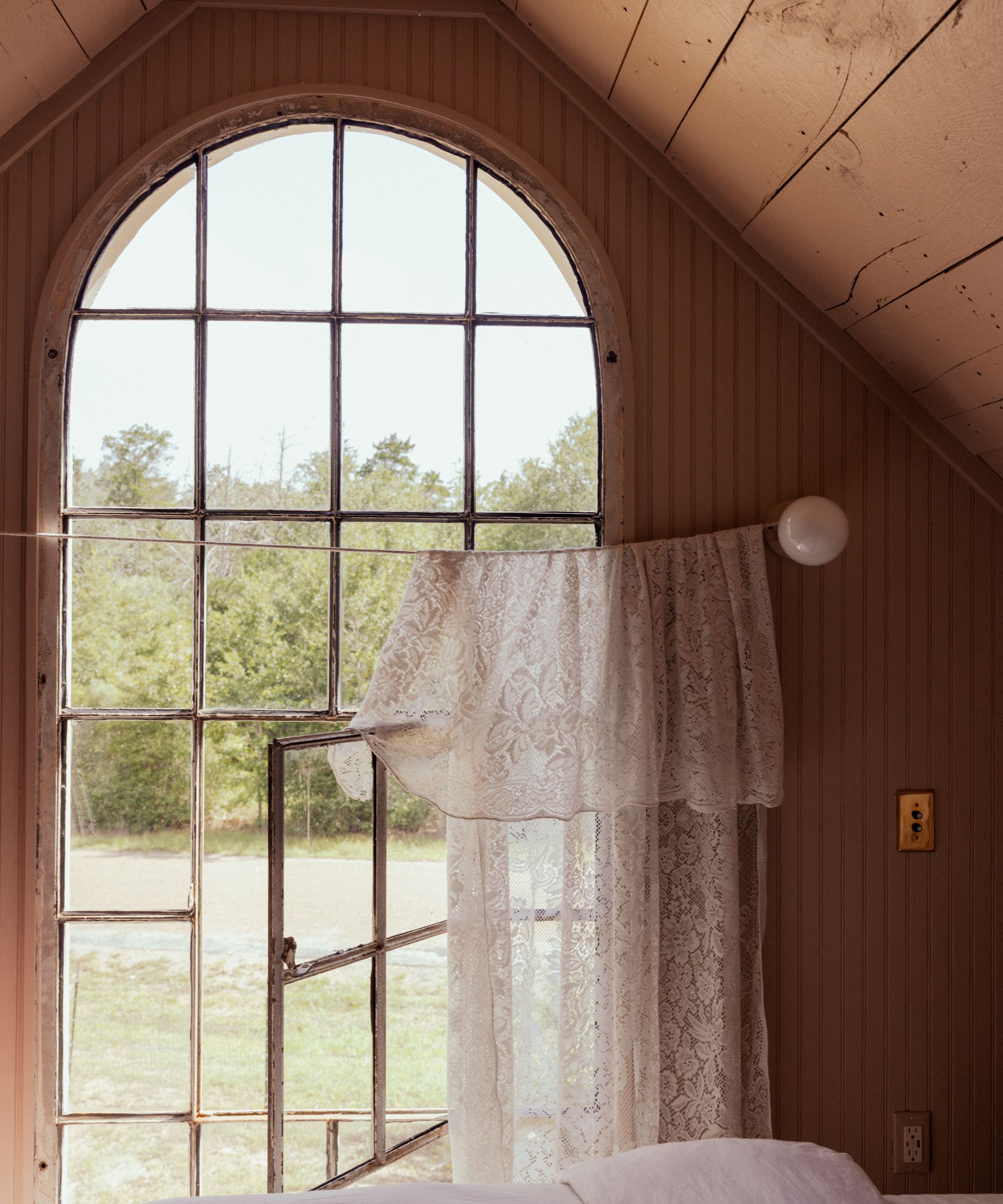 Tall arched window with a simple lace curtain draped across string
