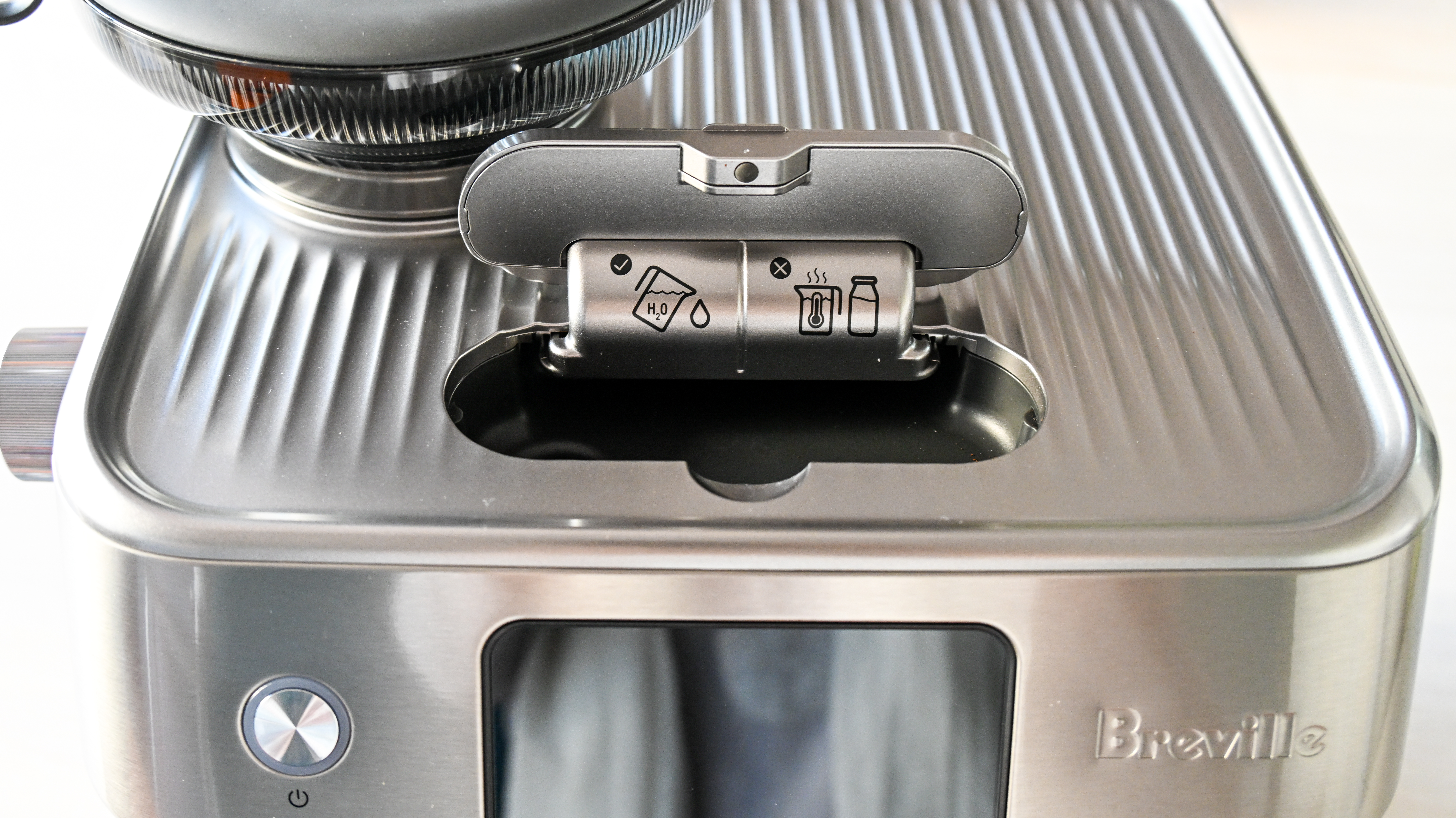 The flap on the top front of the Breville Oracle Jet coffee machine in a raised position, ready for water to be poured into.