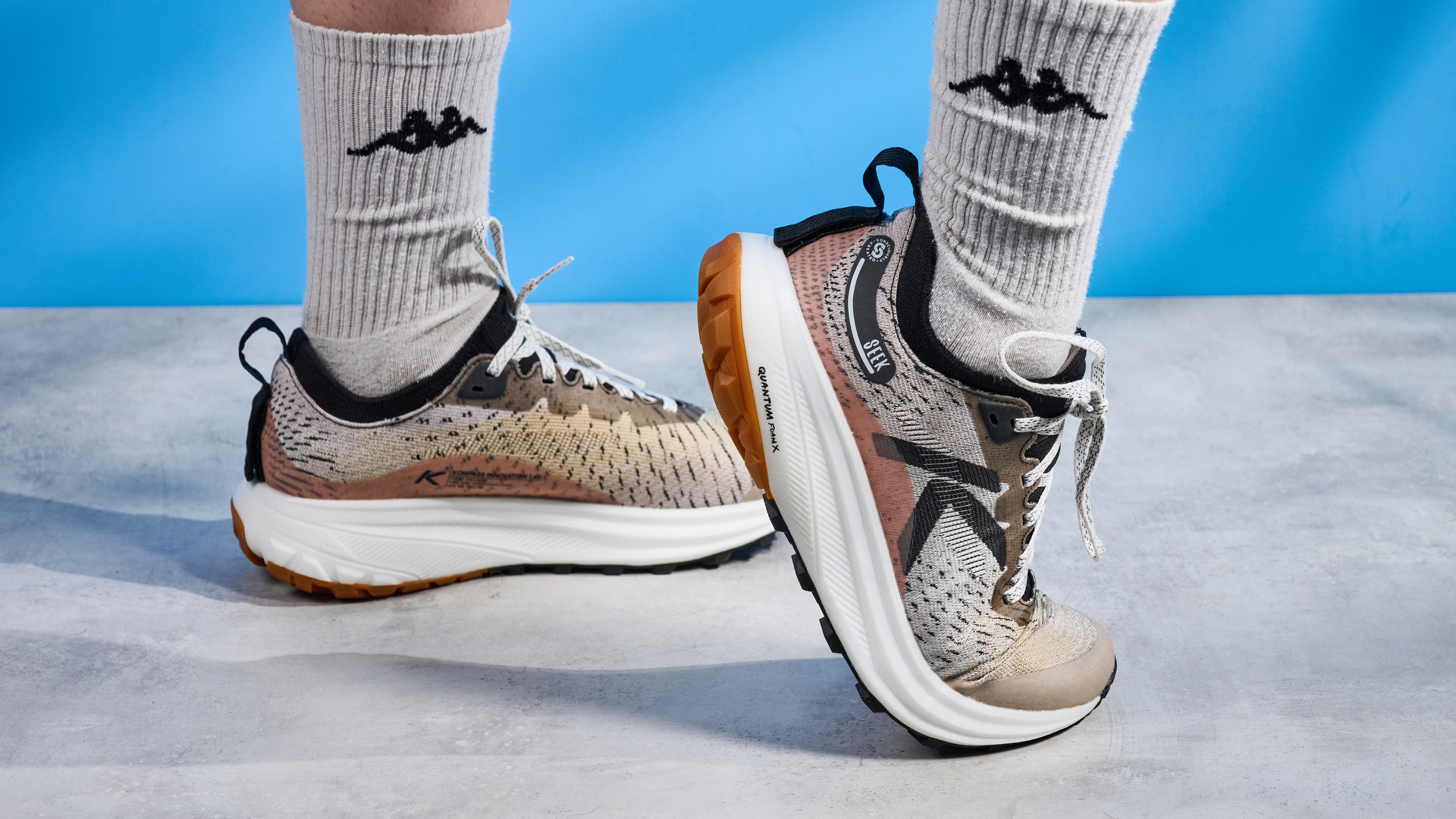 the keen seek trail shoes in brown, black, and beige photographed against the blue tom's guide background