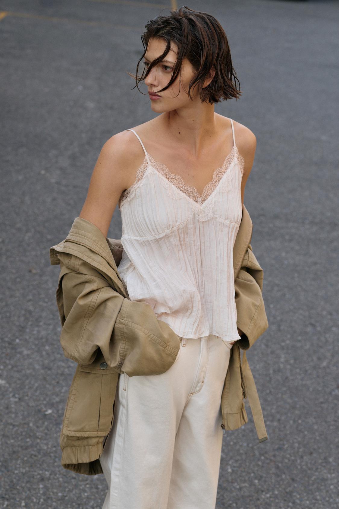 Model wears cream camisole top, cream jeans and beige jacket