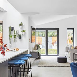 house interior white wall living area and white counter with blue bar stools