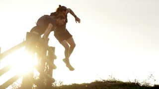 Two people jumping over a gate whilst fastpacking