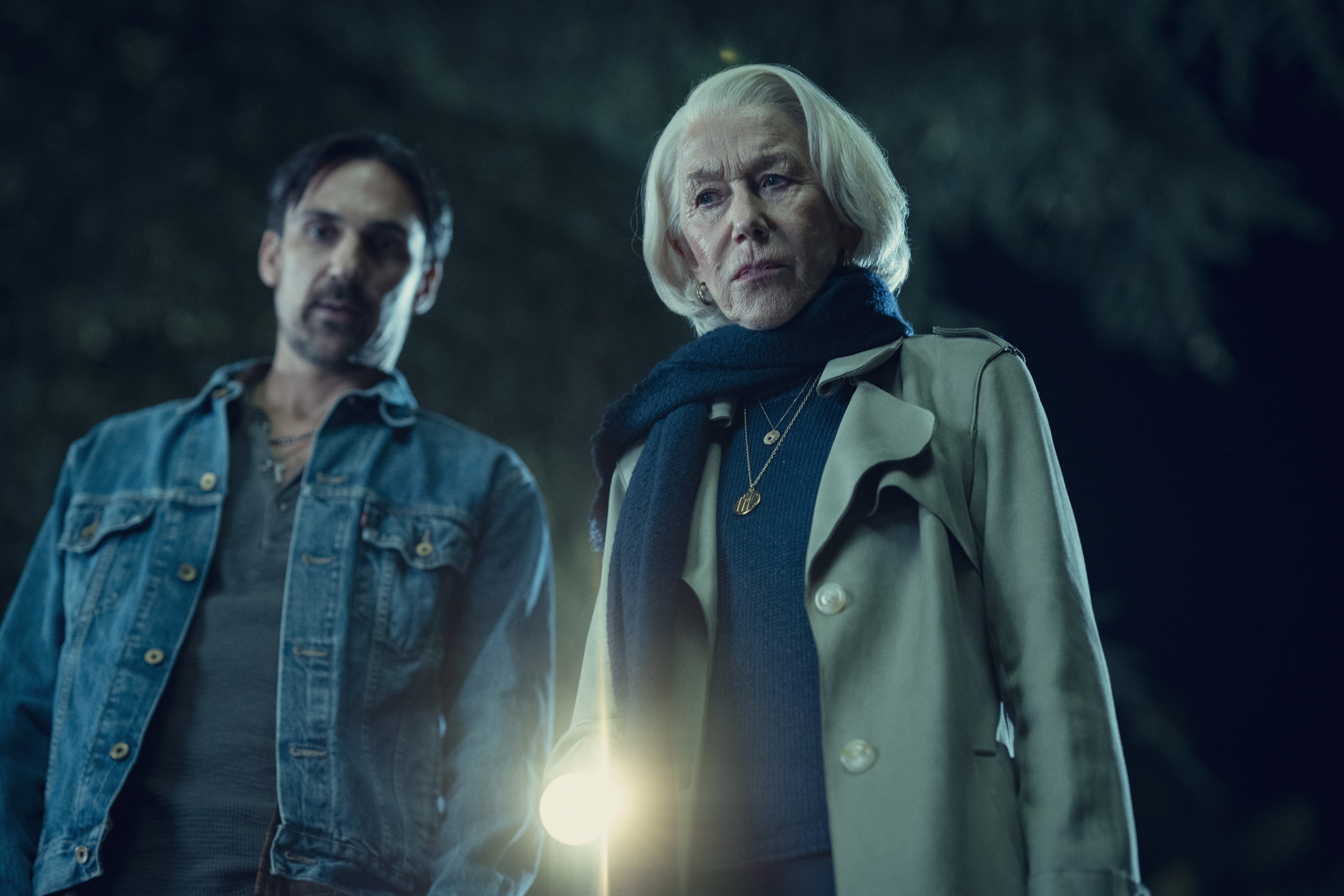 Henry Lloyd Hughes and Helen Mirren point a flashlight down in the dark in a still from the thursday murder club