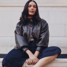 Model wearing a chocolate brown leather jacket and dark denim jorts sold at Simply Be