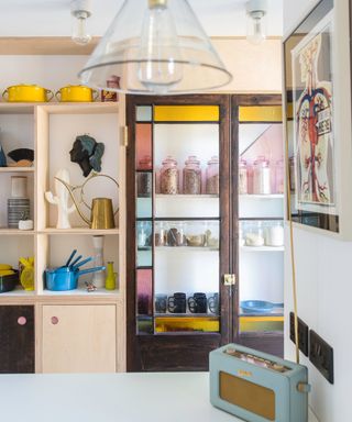 A colorful stained glass cabinet with pops of yellow, pink and blue livens up a kitchen