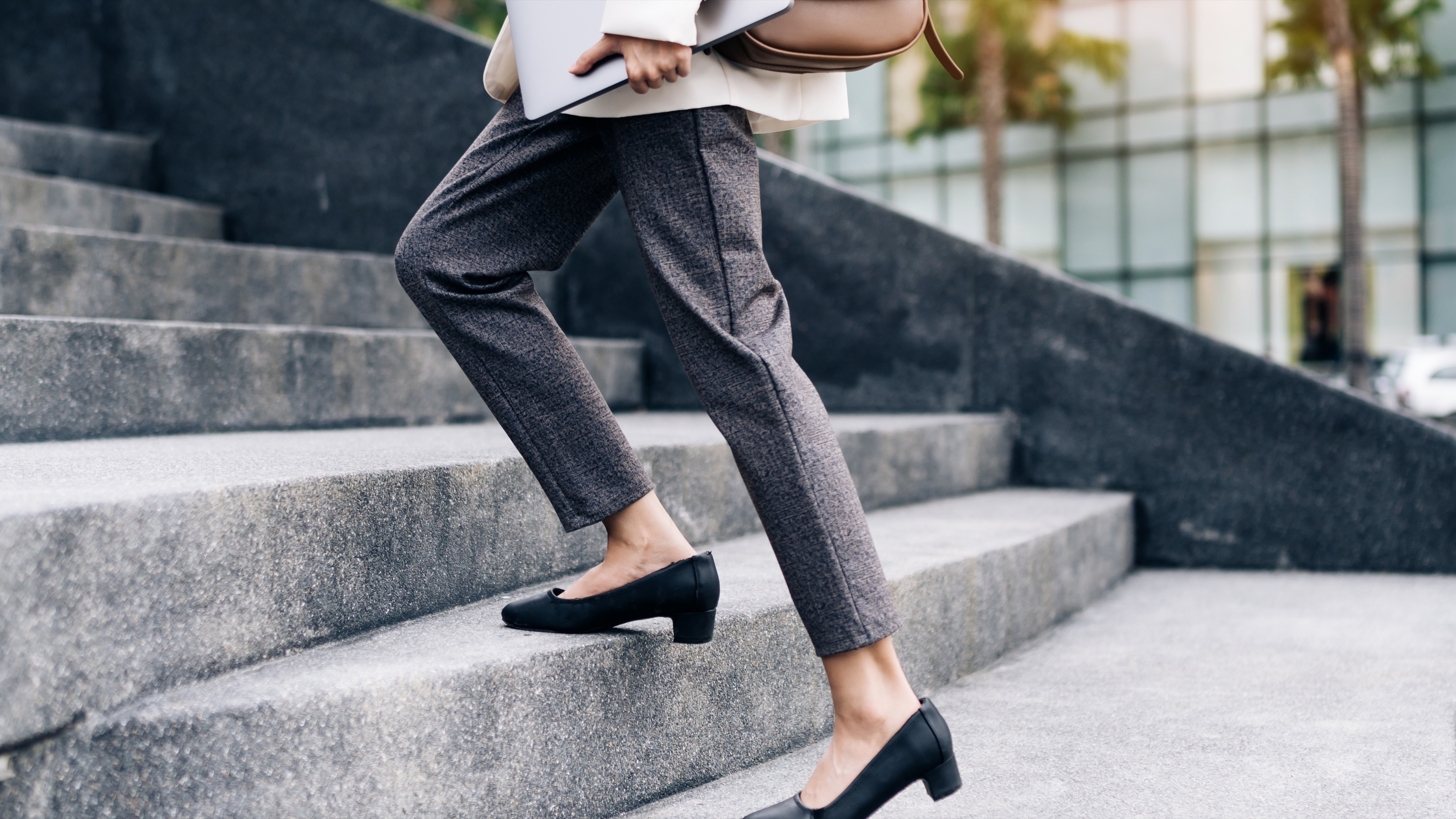 Close up legs of businesswoman hurry up walking she is late time Female business people holding laptop go to office in the modern city foot step on staircase