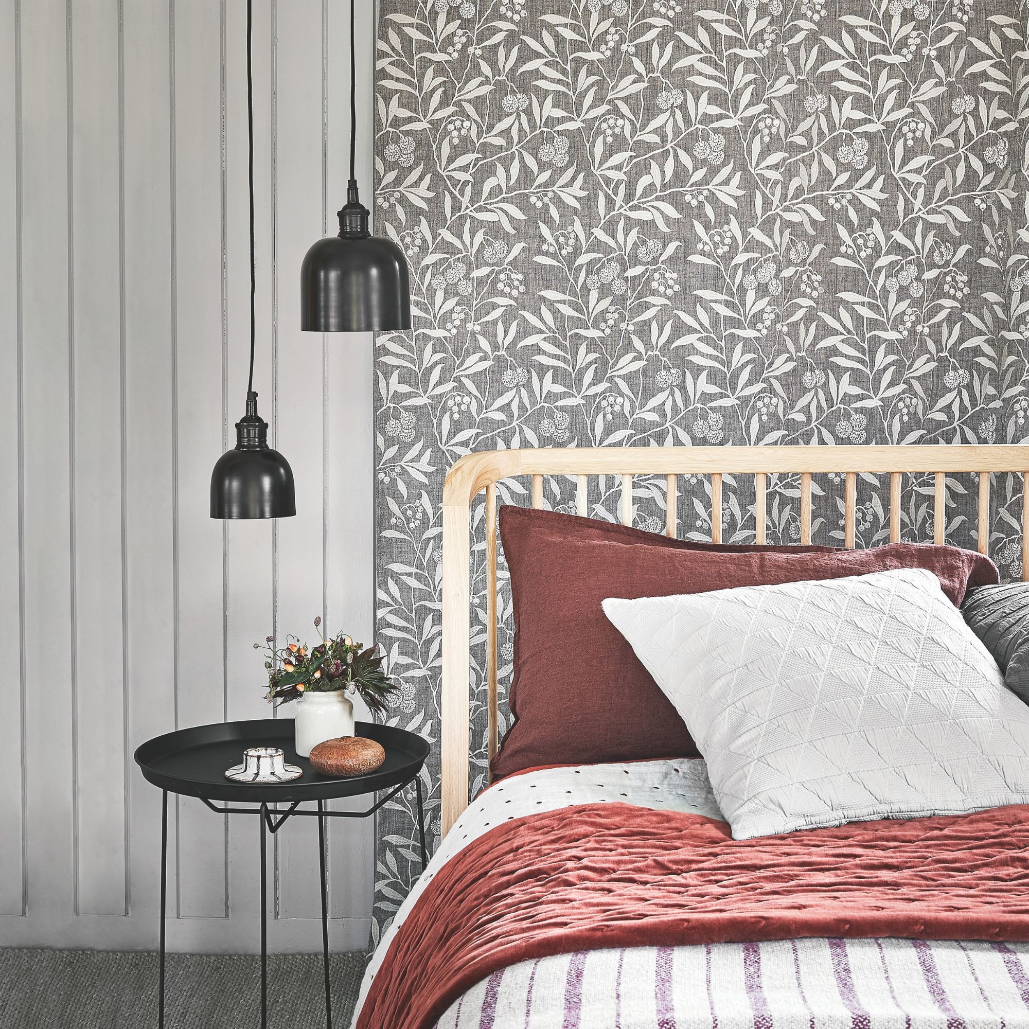 A bedroom with black and red accents and low hanging pendants