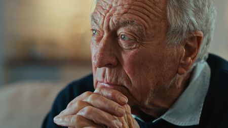 Close up of a senior man sitting alone and looking contemplative 