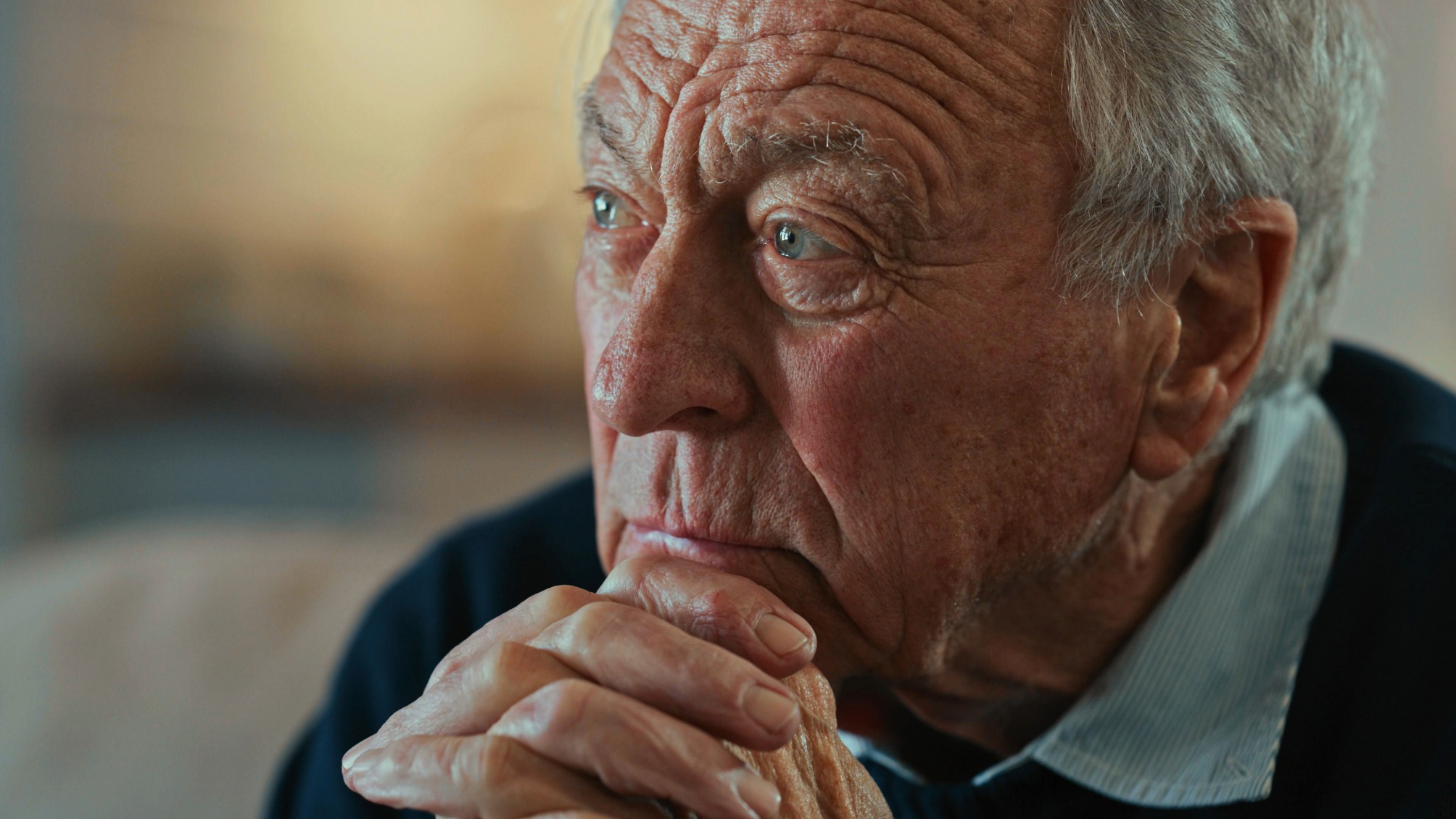 Close up of a senior man sitting alone and looking contemplative 