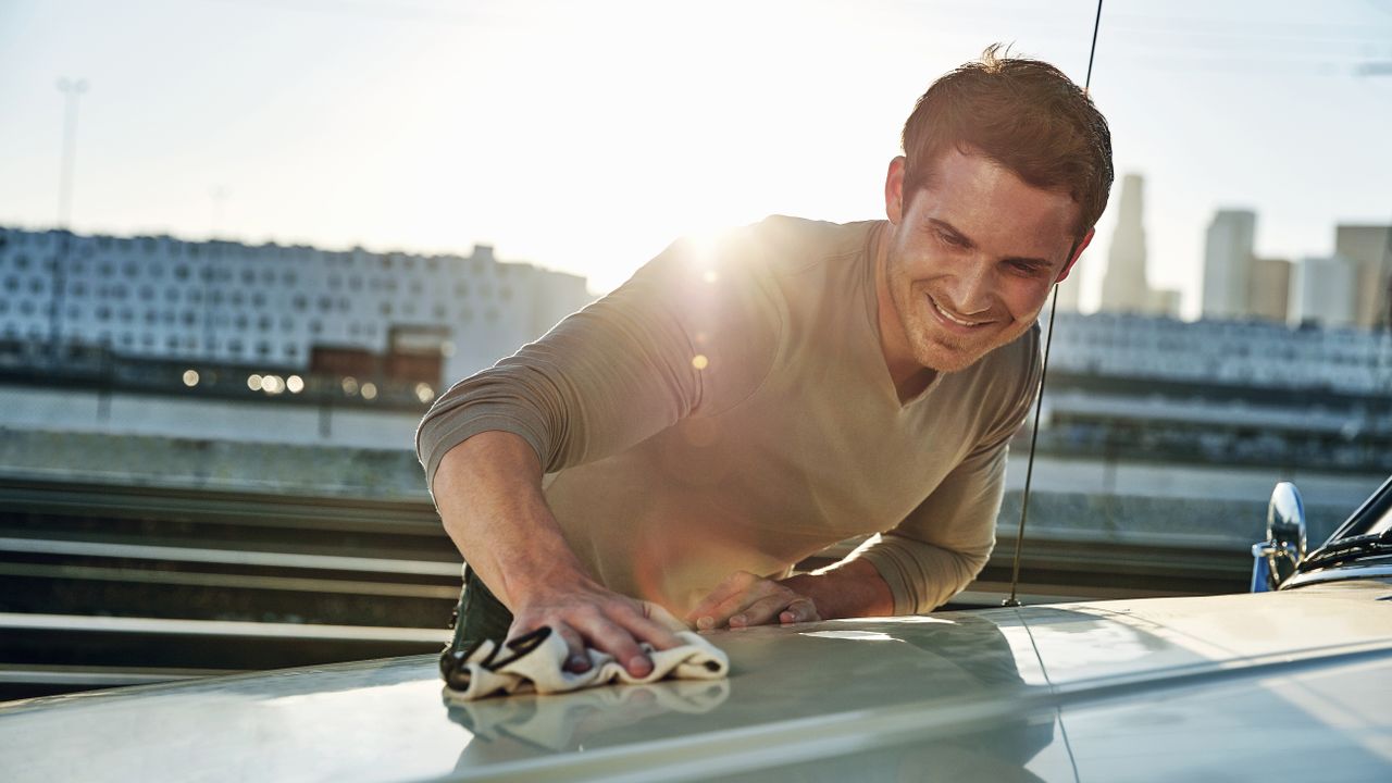 A man polishing his car in the sun with the best car polish