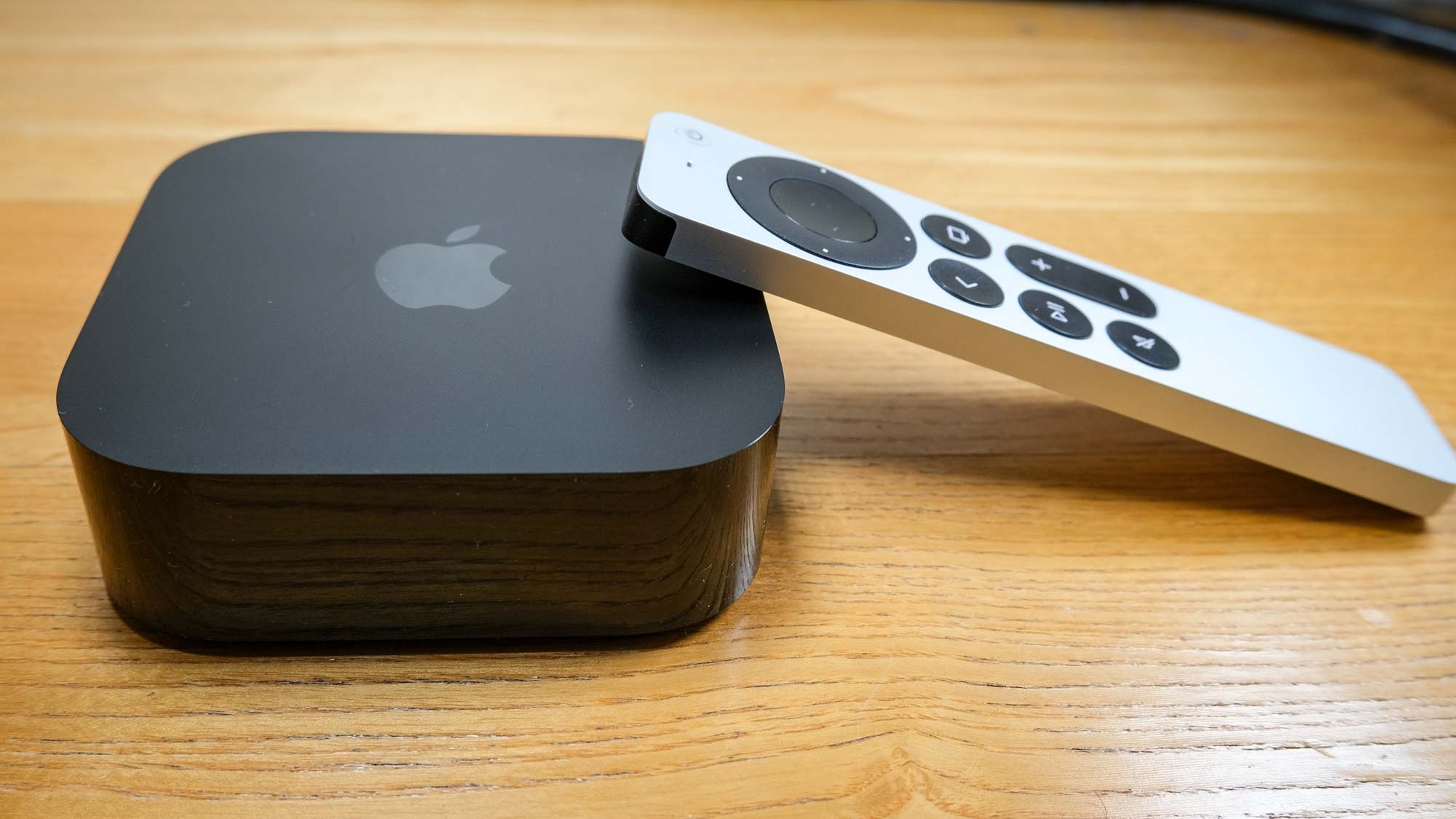El Apple TV 4K (2022), con el Siri Remote presionado hacia su lado derecho.