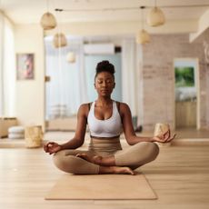 A woman in yoga kit at home doing one of the best workouts for longevity