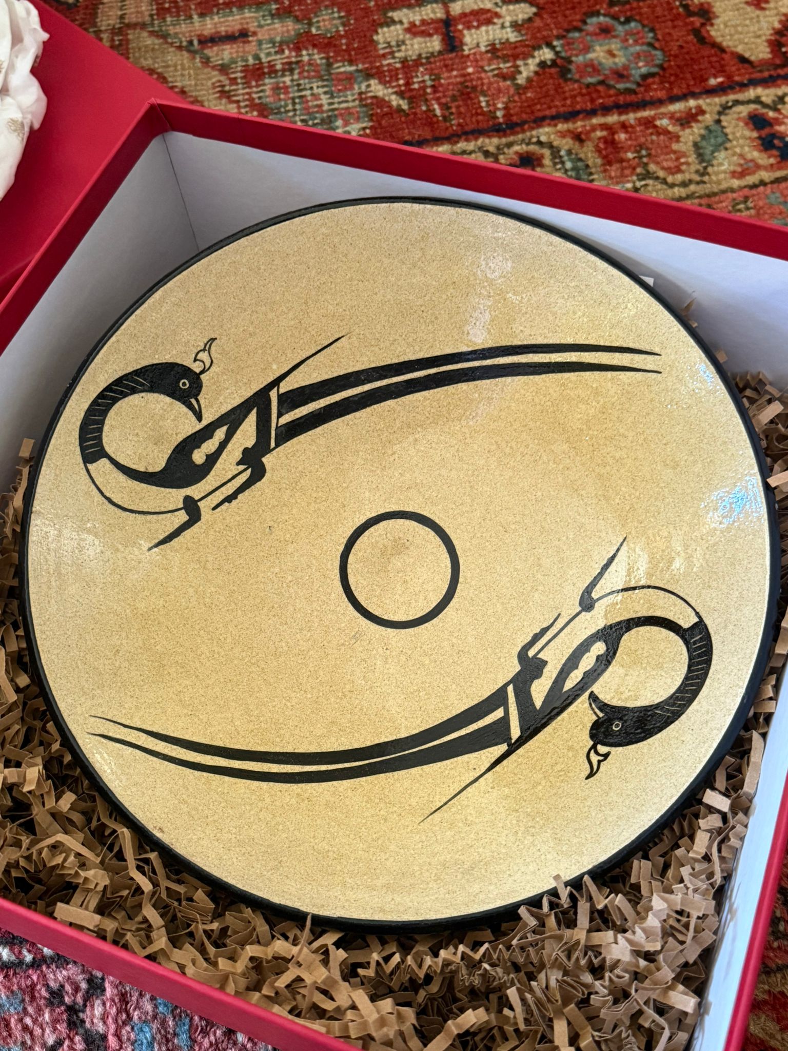 A tan bowl with birds painted on it sitting in a red box