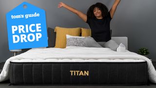 A woman with a bigger build sits on the Titan Plus Mattress, stretching comfortably. A Tom&#039;s Guide price drop graphic (left).