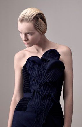 Young female model wearing navy blue Ara dress by Heal Fashion, black tights, pale grey backdrop