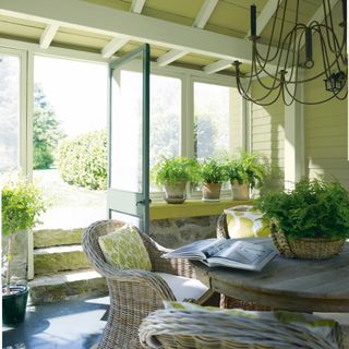 cottage style conservatory/garden room/lime green painted interior, rustic round table, rattan garden chairs, print cushions, ferns in pots