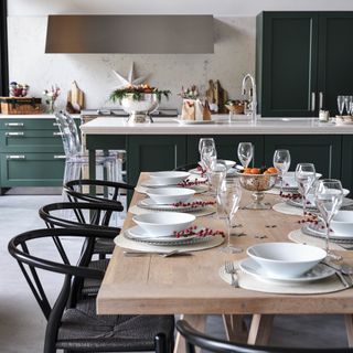 Green shaker kitchen open plan with table set up for Christmas.