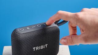 The Tribit PocketGo speaker in black photographed on a blue background.