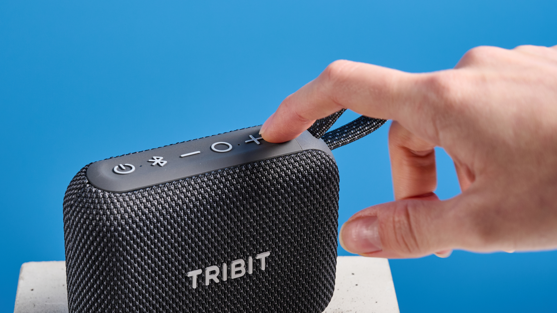 The Tribit PocketGo speaker in black photographed on a blue background.