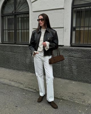 @annabelrosendahl wearing a leather jacket with white jeans and a brown suede Alaia Le Teckel Bag