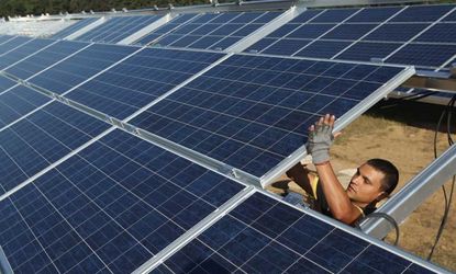 A worker installs solar panels containing photovoltaic cells at the new Solarpark Eggersdorf solar park near Muencheberg, Germany.