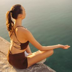 Somatic techniques: A woman meditating by a lake