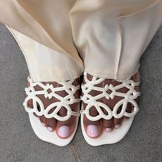A woman wearing cream sandals with a milky lavender pedicure