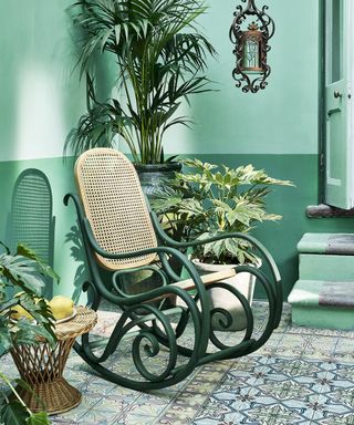 A vintage rocking chair painted up with outdoor paint in a deep green shade