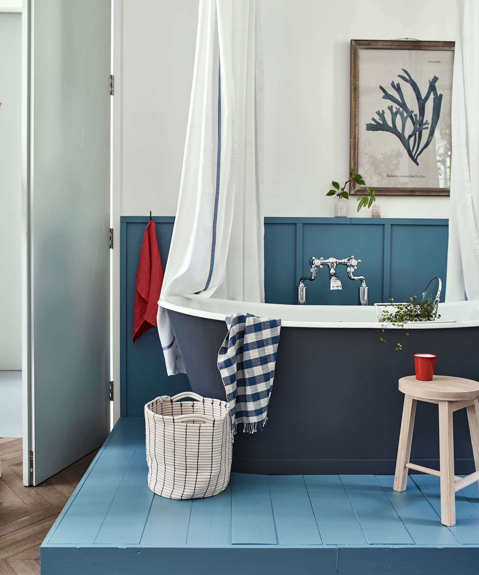A blue nautical inspired bathroom with a freestanding bath