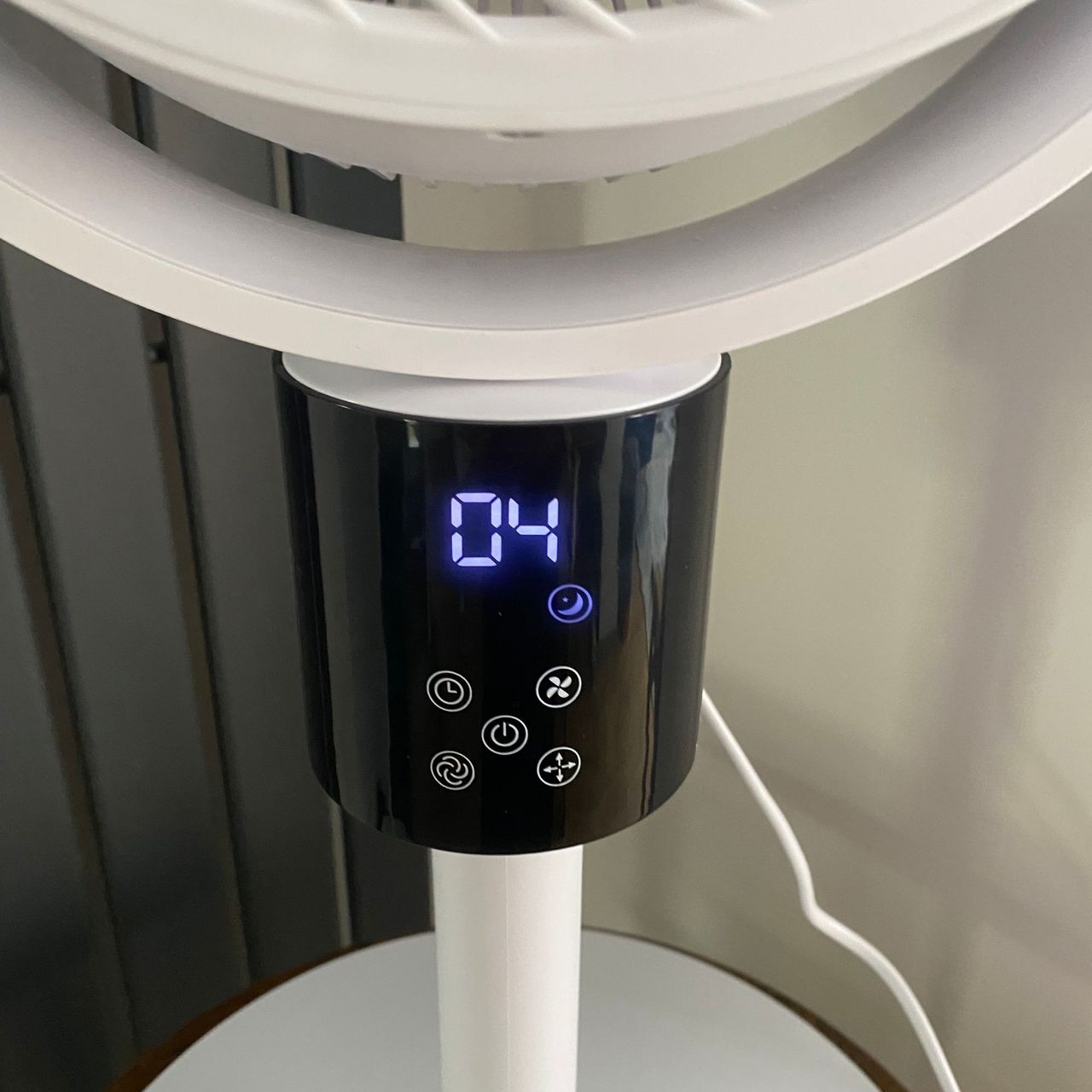 Close up of the display panel of the Silentnight Airmax Pro360 Pedestal Fan in night mode, next to a vertical radiator