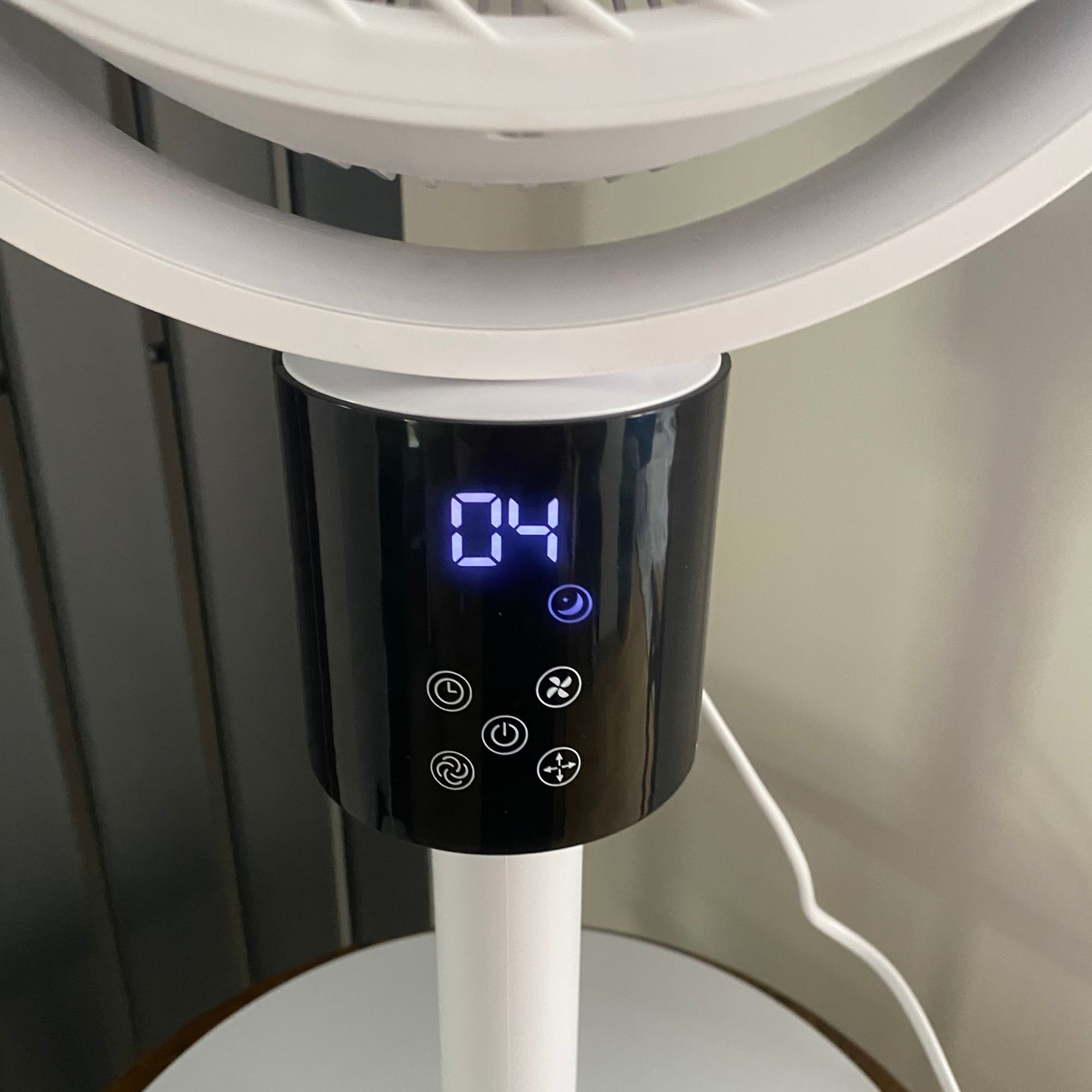 Close up of the display panel of the Silentnight Airmax Pro360 Pedestal Fan in night mode, next to a vertical radiator