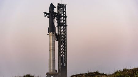 A giant silver and black rocket stands atop a black launch pad at dusk for flight 8