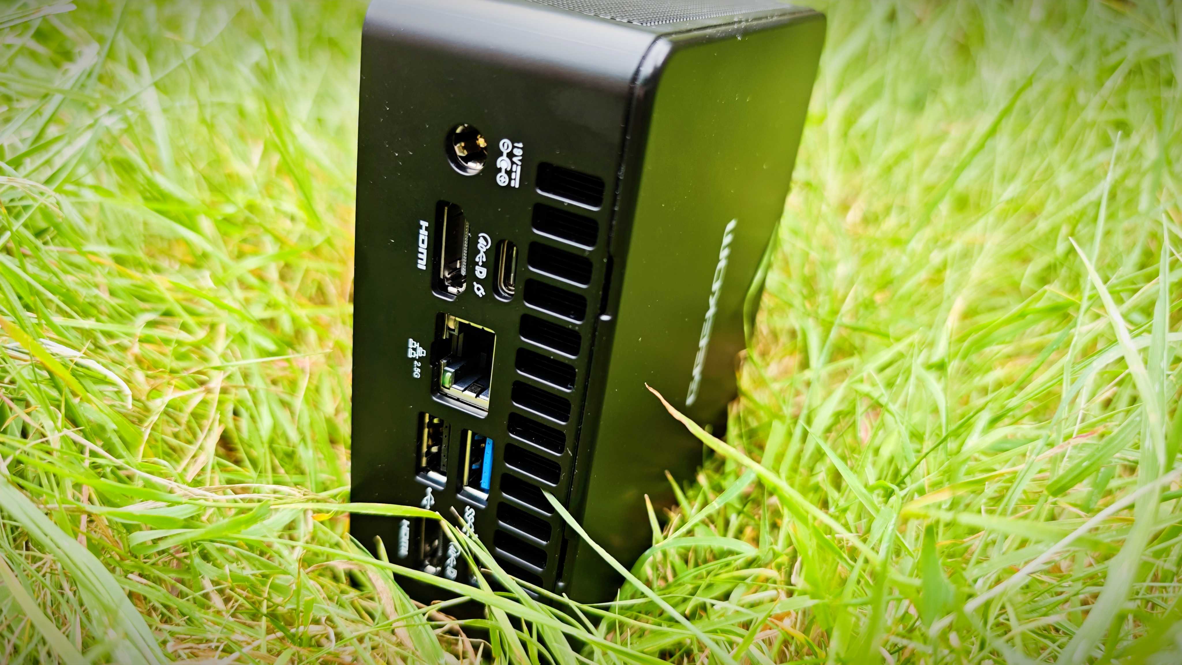 A black Geekom IT15 mini PC sitting in a grassy field