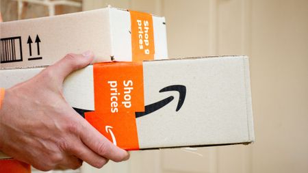 A person holding Amazon boxes.