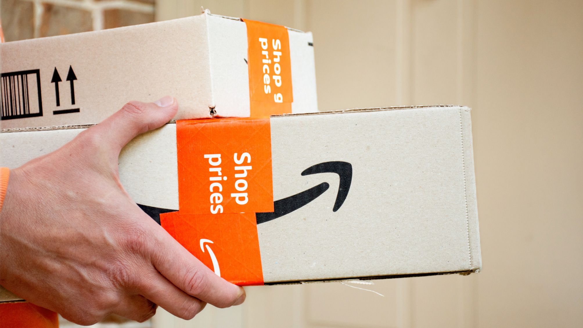 A person holding Amazon boxes.