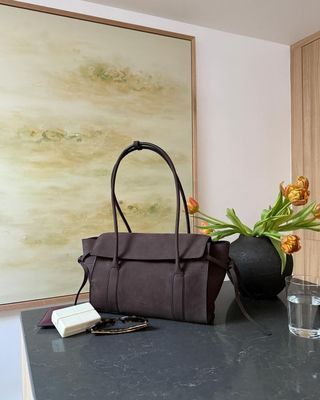 Handbag of on countertop next to flowers