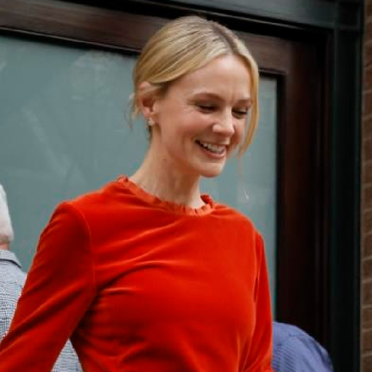 Carey Mulligan wears a persimmon colored top and skirt.