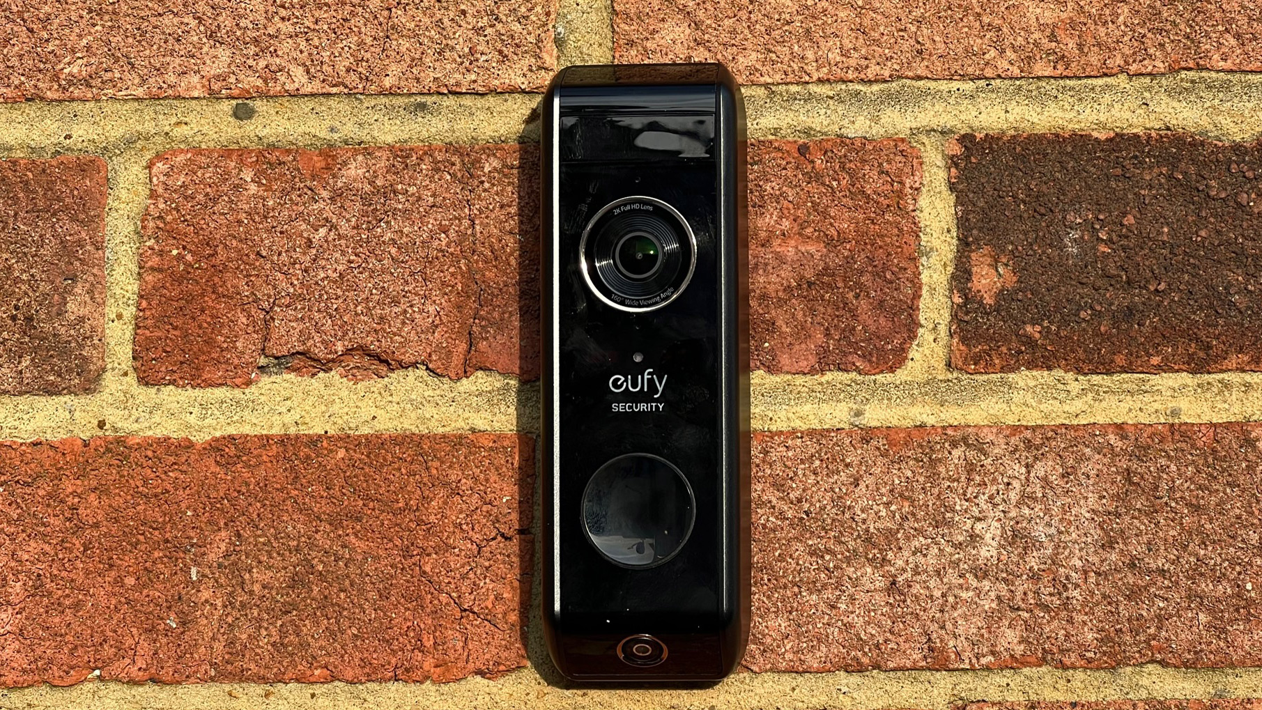 The front view of the Eufy Video Doorbell Dualon a brick wall