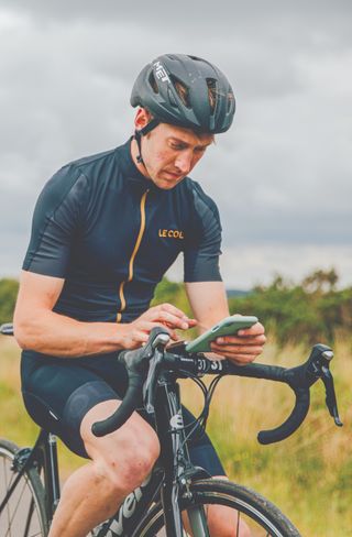 Tom Davidson checking his phone while on a cycle