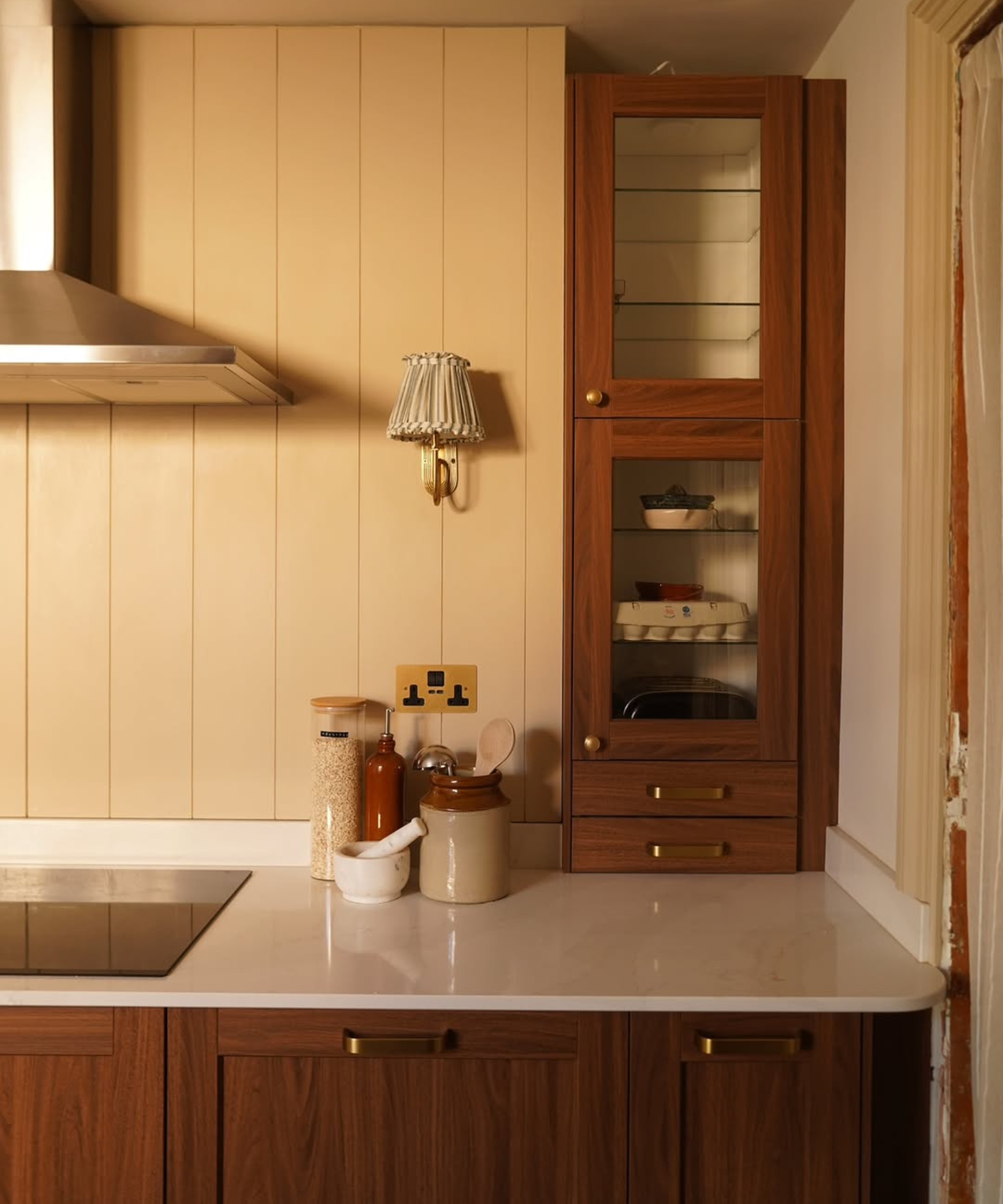 Cream tongue and groove panelling in a kitchen with dark wooden cabinets and a white worktop