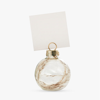 A clear bauble with dried plants on the inside used as a place card holder