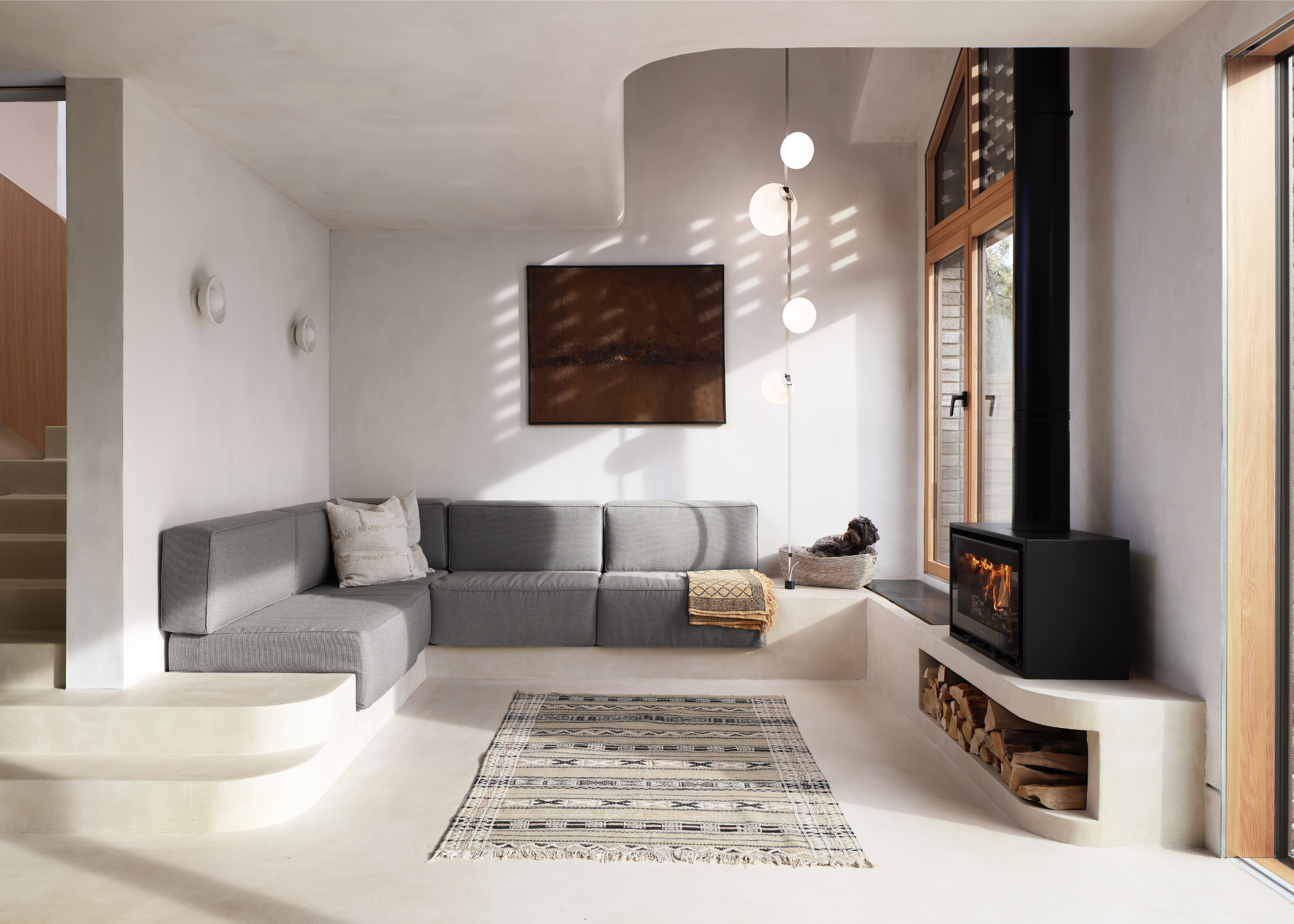 a curving, plastered room with a built in sofa and small fireplace
