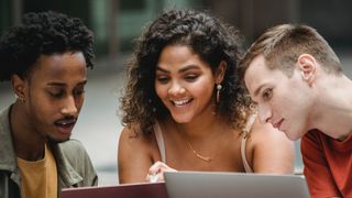 Three young people gathered around laptops