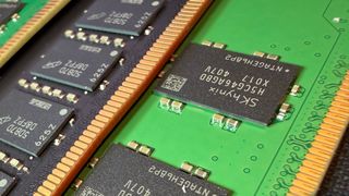 A close-up photo of a pair of Micron and SK Hynix DDR5 DIMMs, showing the memory modules on black/green PCBs