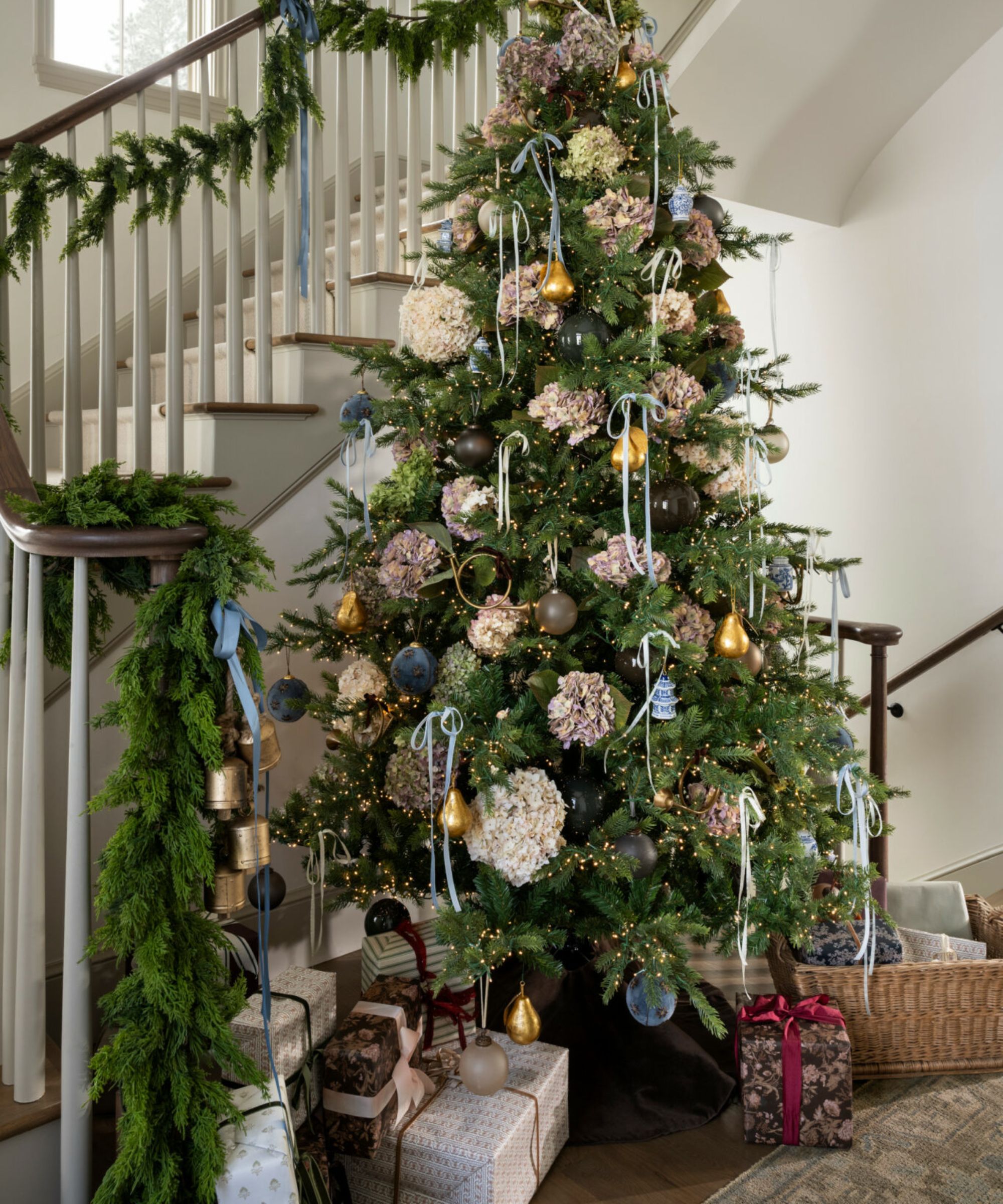 A Christmas tree in an entryway with blue decorations.