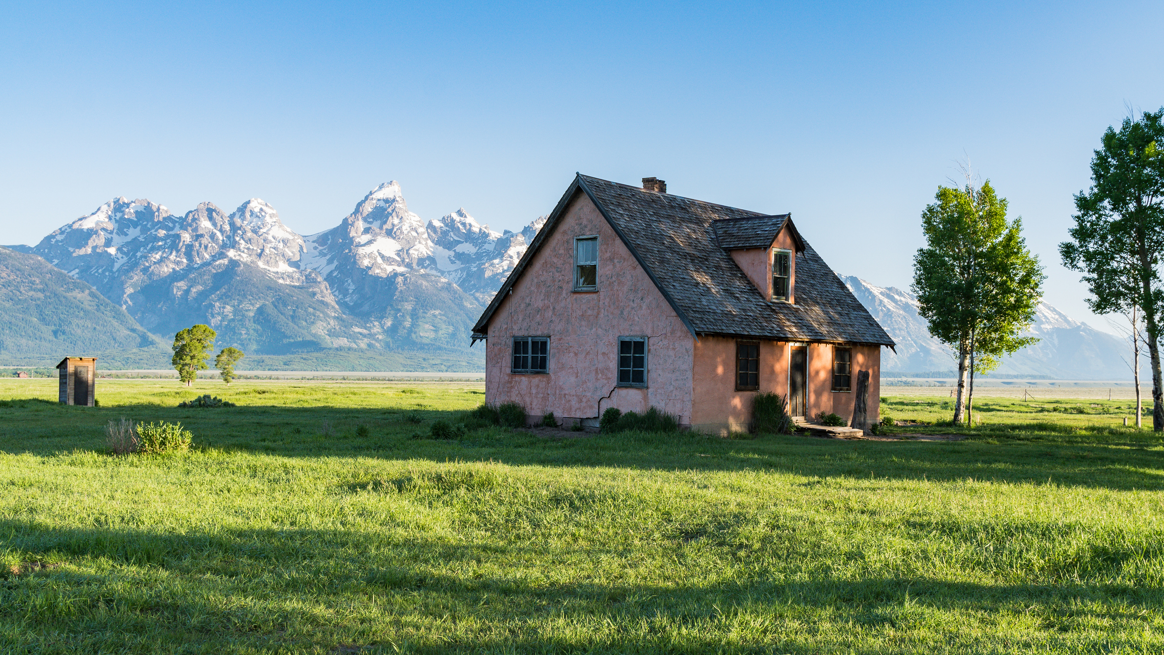 pink cottage in the countryside of Wyoming with mountains in the background