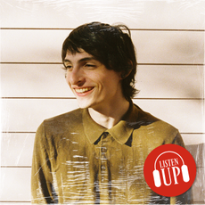 a smiling photo of actor musician finn wolfhard wearing a green button up with a marie claire sticker on it that says listen up