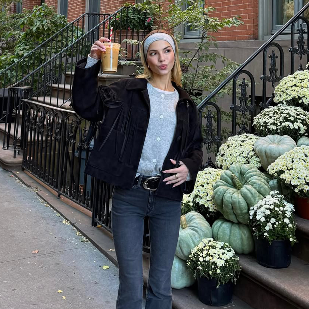Kit Keenan wears a grey sweater and matching headband in front of green pumpkins